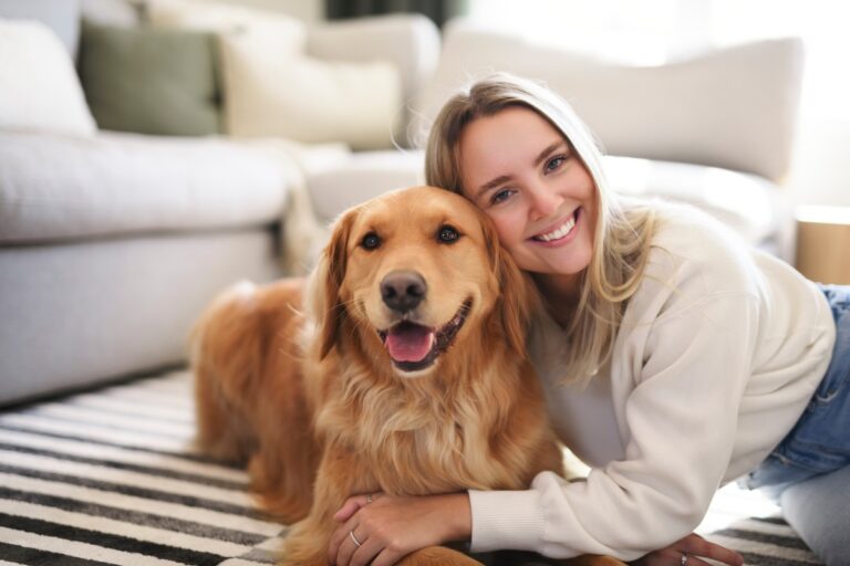 Frau sitzt mit einem Golden Retriever im Wohnzimmer